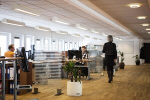 woman walking in an office with two people sitting down