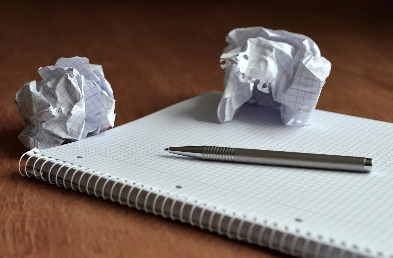 Image of a notebook, pen, and crumpled paper