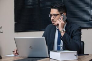 Image of man sitting in a business suit while speaking on the phoen
