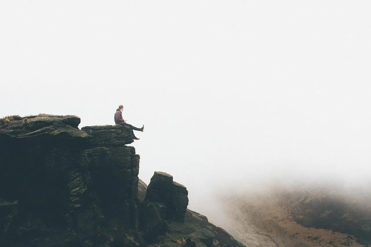 Image of man sitting on rock ledge