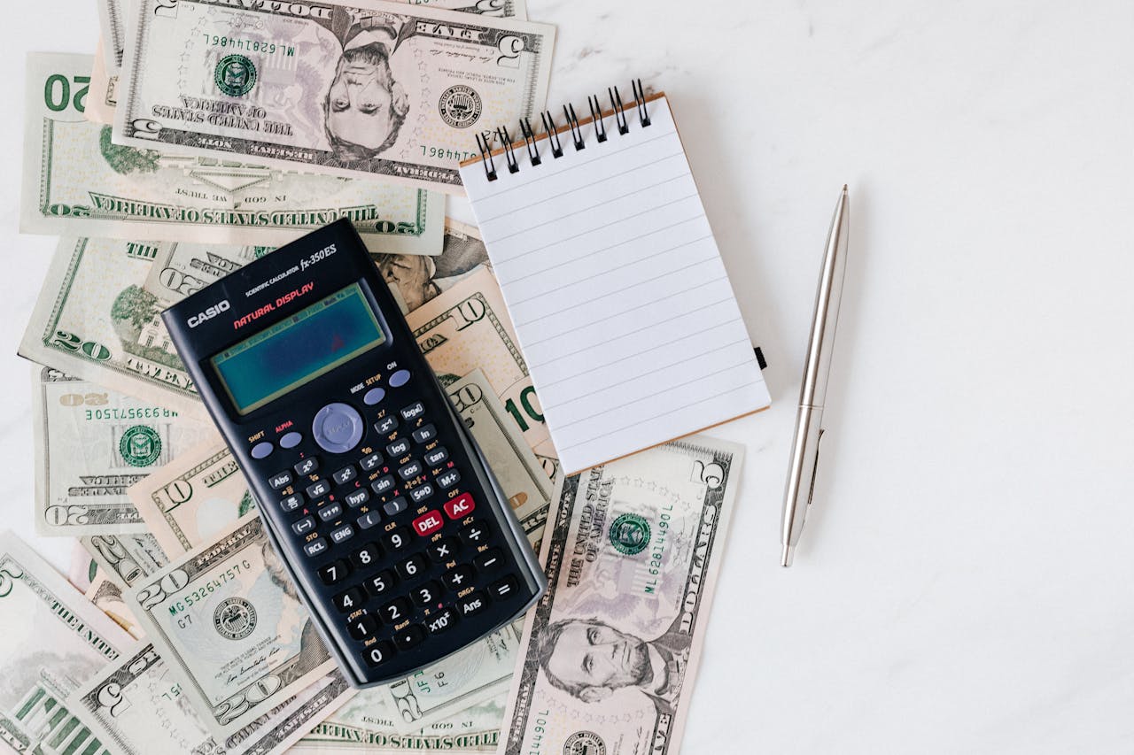 Calculator and notepad on top of a stack of bills
