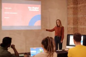 Woman presenting a slide to others in a room