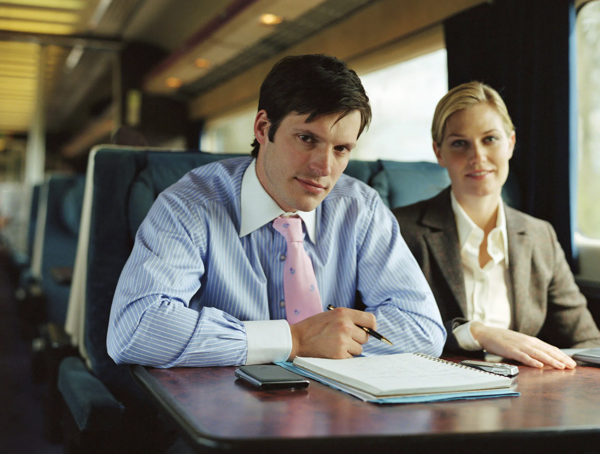 Businessman and businesswoman on train, smiling, portrait